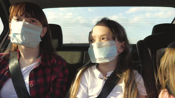 Koruyucu steril tıbbi maskeli sağlıklı genç bir kadın araba kullanıyor. Pandemik koronavirüs konsepti. Özgür bir kız arabayla maskeyle seyahat eder. Virüs ve bakterilere karşı koruma. Bir kız arabaya biniyor. - Fotoğraf, Görsel