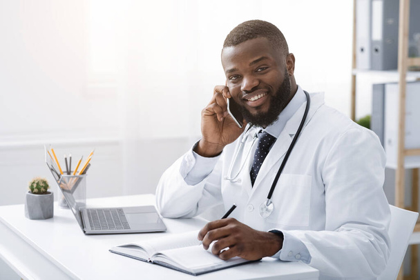 Young doctor talking with patient on smartphone - Photo, image