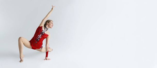 Художественная гимнастика. Красивая спортсменка в костюме перформанса танцует на белом фоне, копирует пространство. Панорама
 - Фото, изображение