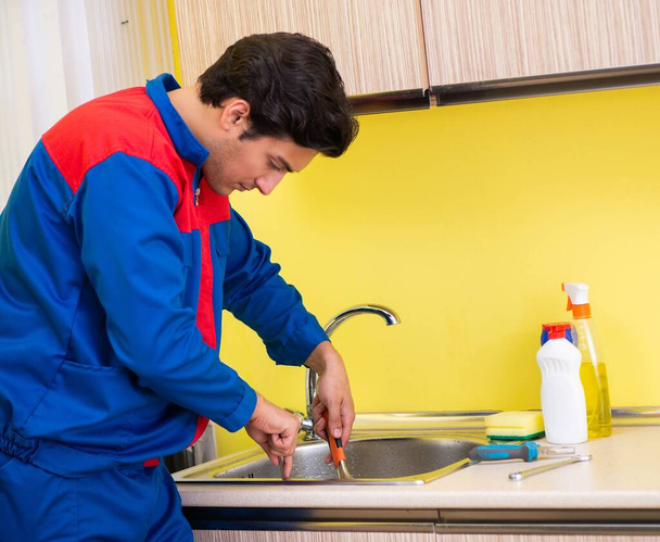 Tesisatçı mutfakta musluğu tamir ediyor. - Fotoğraf, Görsel