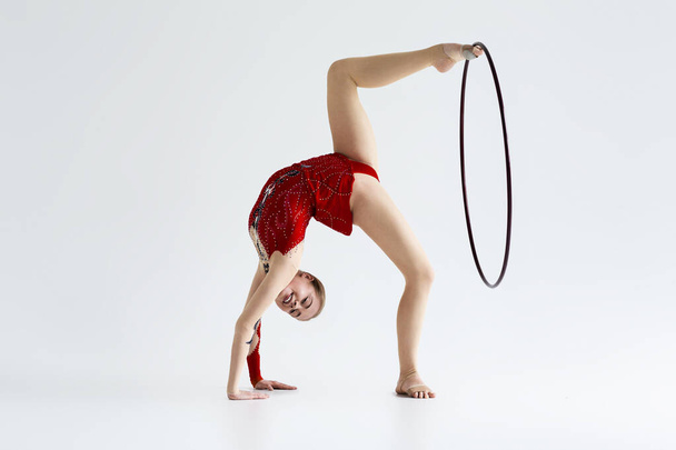Молода гнучка гімнастка робить складний хід з обручем, ізольована на білому
 - Фото, зображення