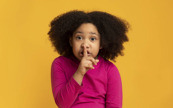 Shh. Serious little african girl showing silence sign, asking be quiet - Фото, изображение
