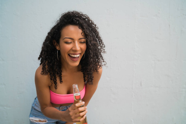 Retrato da jovem afro-americana latina desfrutando e bebendo uma garrafa de cerveja. Conceito de estilo de vida. - Foto, Imagem