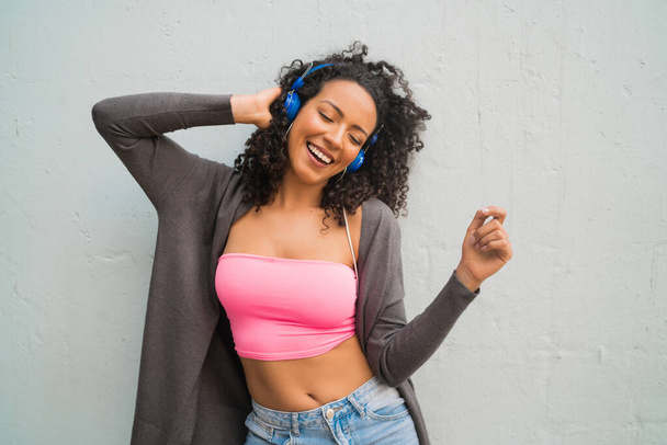 Портрет молодої афро-жінки, яка насолоджується і слухає музику з синіми навушниками. Технологія та концепція способу життя
. - Фото, зображення