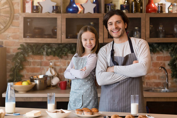 Père et fille posant dans des tabliers tout en cuisinant ensemble dans la cuisine
 - Photo, image