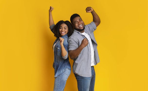 Evviva! Felice coppia afro-americana che celebra il successo con pugni alzati
 - Foto, immagini