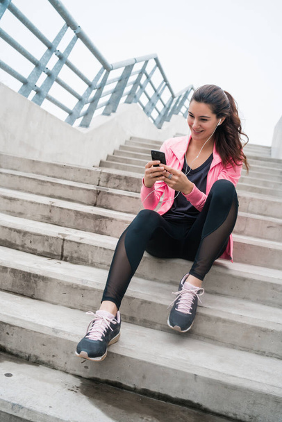 Portrait of an athletic woman using her mobile phone on a break from training. Sport and health lifestyle. - Foto, immagini