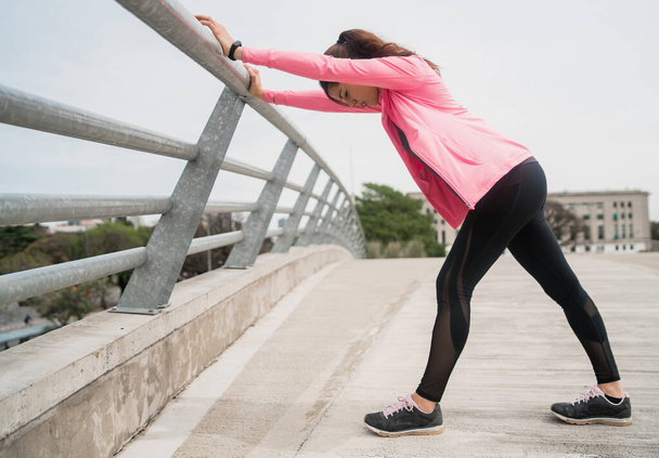 Portrait of an athletic woman stretching legs before exercise outdoors. Sport and healthy lifestyle. - 写真・画像