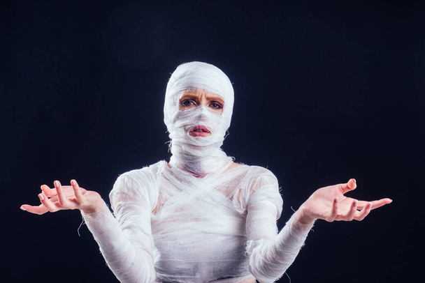 Okouzlující mumie žena v obvazech po celém těle v ateliéru černé pozadí. Halloween party nebo plastické chirurgie oběť koncept - Fotografie, Obrázek