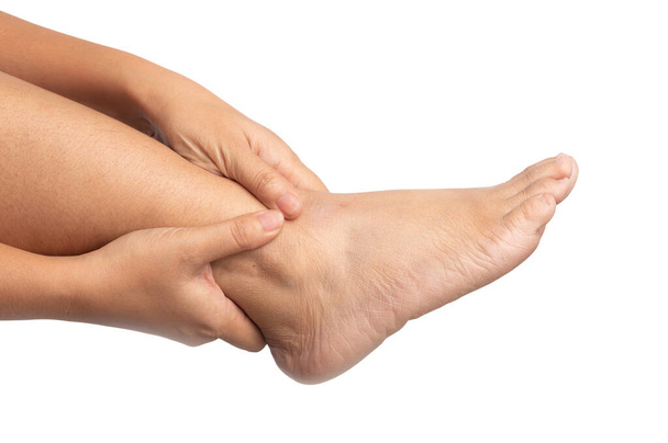 Mujer con dolor en el tobillo usando dos manos sosteniendo la pierna y masajeándola dolorosamente en aislado. Malestar alrededor del tobillo, que a menudo incluye articulaciones o tendones que sostienen los músculos y huesos que conectan la parte inferior de la pierna con el talón. (isquiotita
) - Foto, imagen