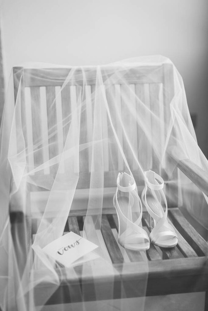 trouwschoenen en sluier achtergrond. Bruidsschoenen en huwelijksgelofte met sluier achtergrond. Zwart-wit. - Foto, afbeelding