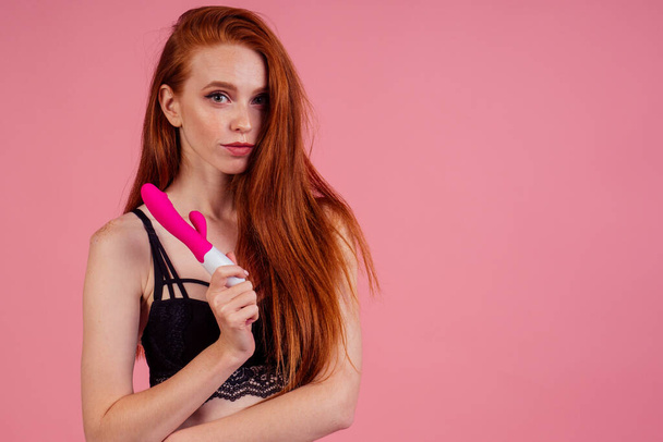 redhaired ginger woman with sex self clit and vagina stimulation and wearing black lace bra and underpants in studio pink background - Foto, Imagen