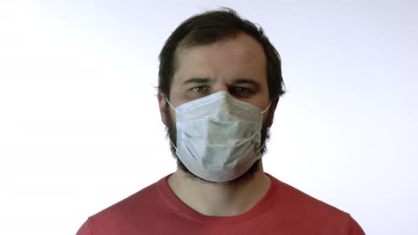 Uomo in maschera medica nervosamente in piedi e guarda la fotocamera. Panico del coronavirus
 - Filmati, video
