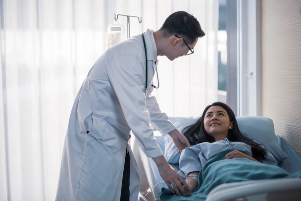 Médico y paciente discutiendo algo mientras revisa la salud en la cama en el hospital
 - Foto, Imagen