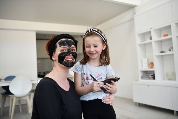 Сім'я вдома лікування краси під час пандемії коронавірусу залишається на домашньому карантині. Мати і дівчинка дочка роблять маску для обличчя
. - Фото, зображення