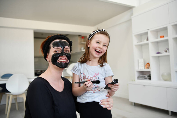 Family at home beauty treatment during coronavirus pandemic stay at home quarantine. Mother and little girl daughter  make a facial mask. - Fotoğraf, Görsel