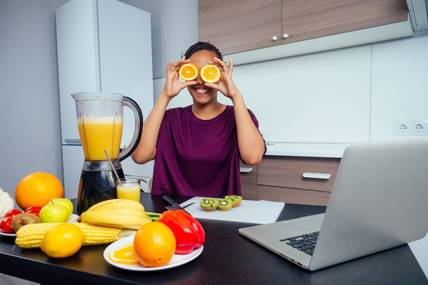 latino woman working at juice bar and cutting fruits, making fresh smoothies from bananas,orange and melon. she useing eco metal reusable tubes and glass - Foto, afbeelding