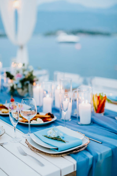 Candelabro Mesa de comedor decoración de fiesta. Decoración de mesa para comer con velas al aire libre cerca del mar. Diseño de color azul cielo
. - Foto, imagen