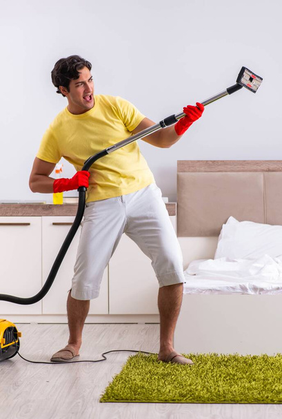 Young handsome man cleaning in the bedroom - Photo, image