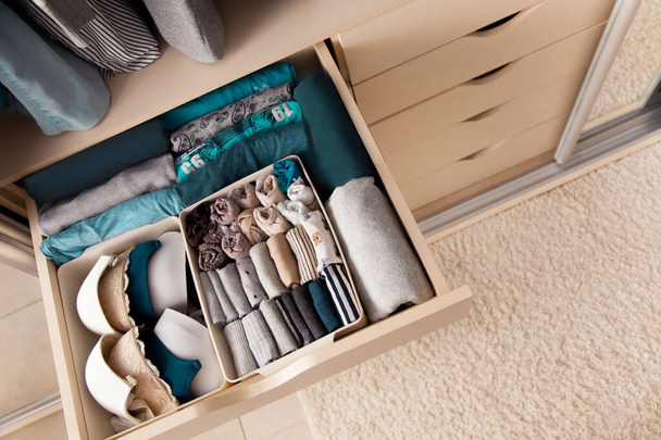 Top view of womens things and accessories of blue color are in the drawer of the wardrobe closet during tidying by the lady fly system. Convenient and intelligent storage concept - Fotografie, Obrázek