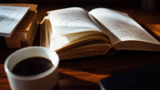 ノートとコーヒーをテーブルの上に置く古いハードカバーアーカイブの本.研究と教育の概念.本を読んで,難しい文学から勉強.自宅でリラックスした時間.物理学と数学の研究.知識 - 写真・画像