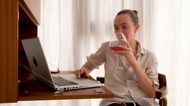 Woman working on a laptop with a glass of wine - 映像、動画
