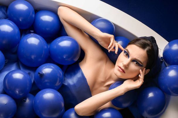 Portrait de jeune femme à la mode avec des ballons à air couché dans la baignoire
 - Photo, image