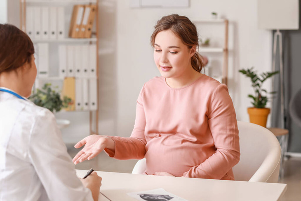Young pregnant woman visiting doctor in clinic - Foto, Imagen