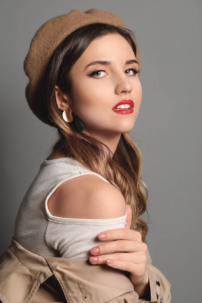 Fashionable young woman on grey background - Foto, afbeelding