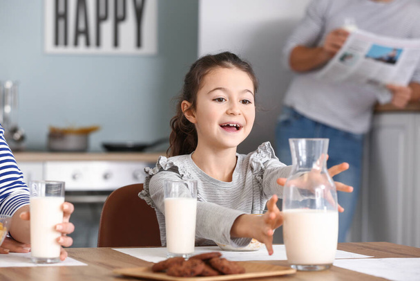 Маленькая девочка пьет молоко во время завтрака дома
 - Фото, изображение