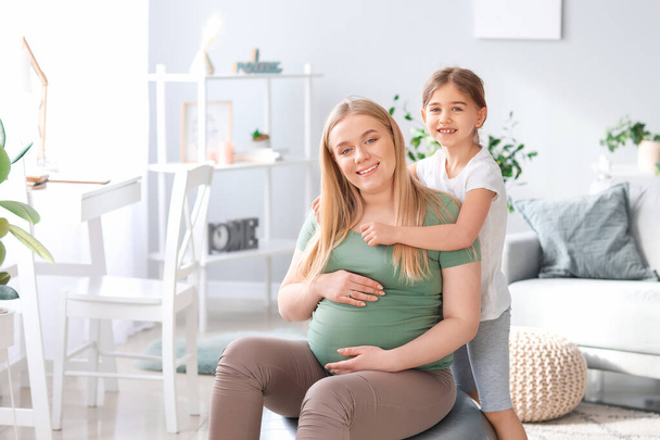 Mulher grávida desportiva e sua filhinha em casa
 - Foto, Imagem