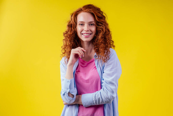 redhair ginger curly student woman arms crossed on chest in studio yellow background.foreign language learning concept - Photo, Image