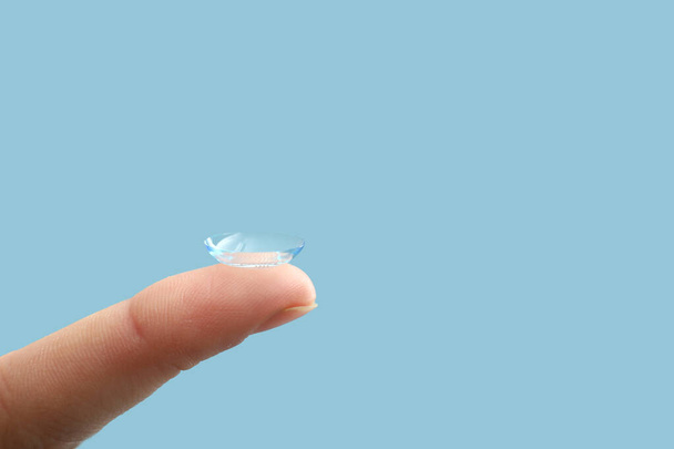 Ženský prst s kontaktní čočkou na barevném pozadí - Fotografie, Obrázek