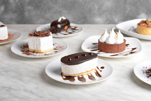 Sabrosos pasteles sobre mesa blanca
 - Foto, imagen