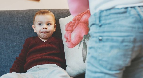 Caucasian mother explaining something to her little son while sitting on sofa and thinking - Fotografie, Obrázek