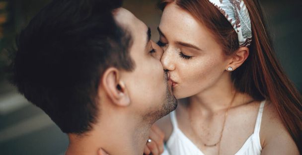 Lovely ginger woman with freckles kissing her lover while having a walk in the park - Photo, Image