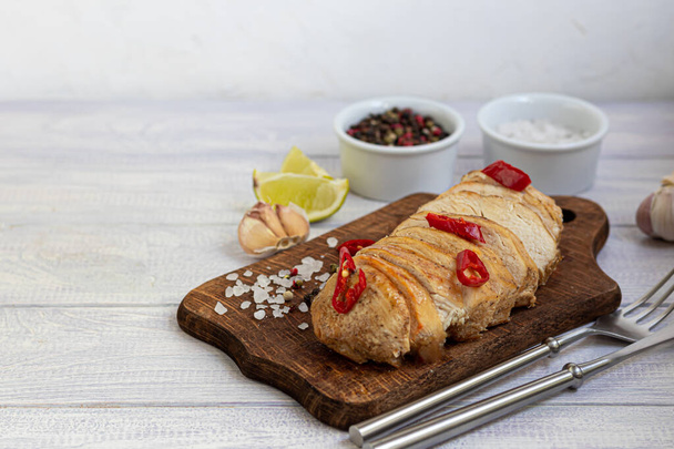 Cooked chicken breast in the oven, sliced on a wooden board. Served with chili pepper. Nearby are garlic, coarse salt, lime, peppercorns. Dietary nutrition. Copy space - Фото, изображение