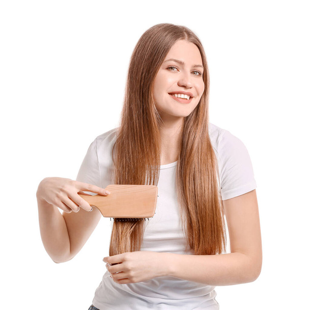 Beautiful young woman brushing hair on white background - Zdjęcie, obraz