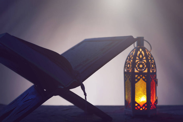 Lanterne arabe ornementale avec bougie allumée qui brille dans le Coran noir et saint. Carte de vœux festive, invitation pour le mois saint musulman Ramadan Kareem
 - Photo, image