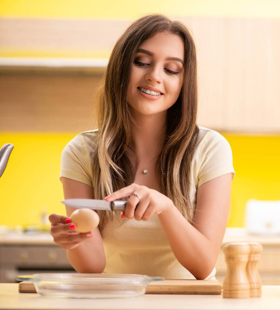 Young woman preparing salad at home in kitchen - Foto, afbeelding