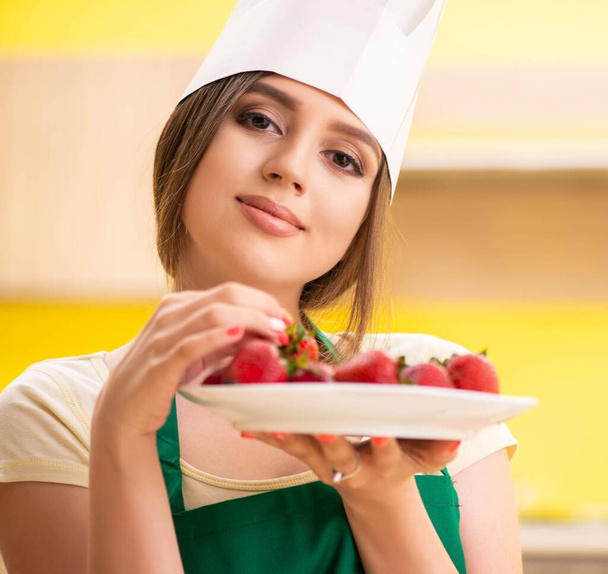 Young female cook eating strawberries - Photo, Image
