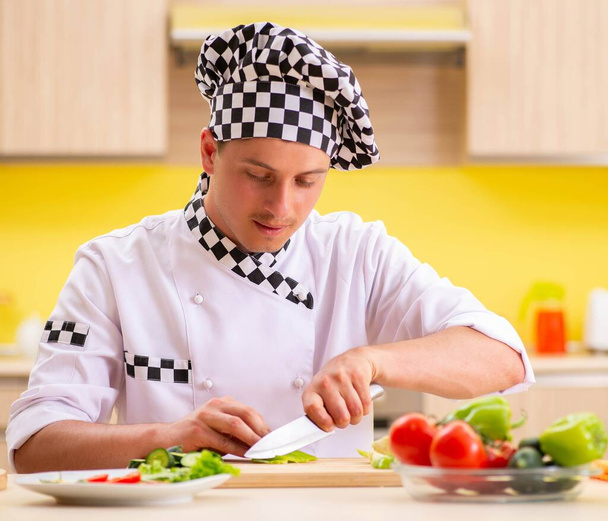 若いプロの料理人がキッチンでサラダを準備 - 写真・画像