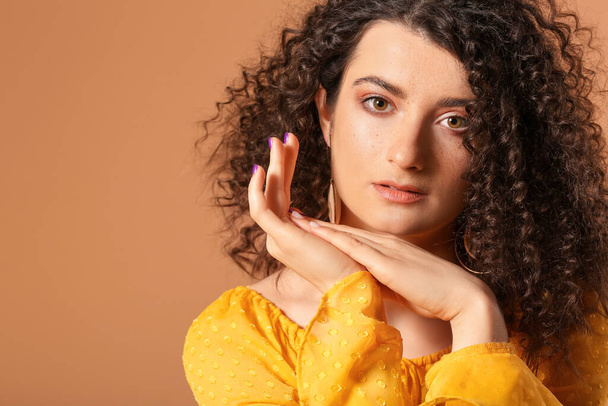 Young woman with beautiful curly hair on color background - Fotó, kép