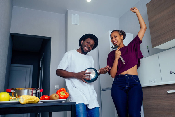 Beautiful young Afro American couple is smiling while dancing in kitchen - Foto, Imagen