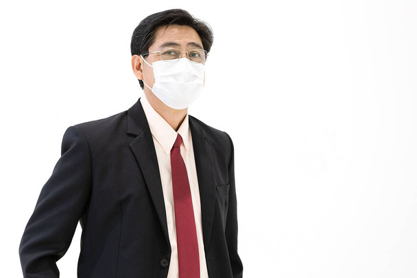 顔に外科用衛生保護マスクを着用し、カメラを探してスイートでシニアエレガントなエグゼクティブビジネスマン,安全のためのコロナウイルスや健康管理の危機を防ぐためのアイデア. - 写真・画像