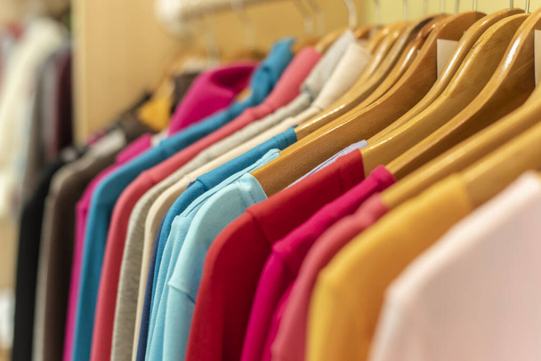 helder gekleurde kleding op een rek winkel display verkoop  - Foto, afbeelding