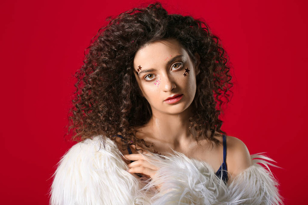 Jeune femme avec de beaux cheveux bouclés et un maquillage créatif sur fond de couleur
 - Photo, image