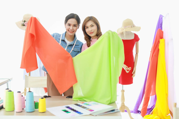 Zblízka záběr šťastný dva krásné asijské ženské módní návrháře výběru tkaniny z odrůdy tkaniny pro šití jejich nové kolekce dohromady. - Fotografie, Obrázek