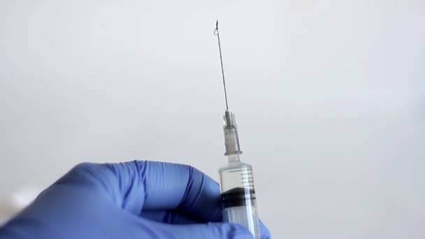 Doctor's hands in blue medical glove holds a medical syringe with injection, releases air from syringe with medicine and ready to make a injection. Concept healthcare and medicine, of anti-virus protection Coronavirus, COVID-19 and other  viruses - Filmmaterial, Video