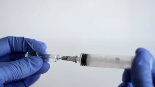 Doctor's hand in blue medical glove gaining a medical syringe injection from ampoule. Concept healthcare and medicine, of anti-virus protection Coronavirus, COVID-19 and other dangerous viruses - Felvétel, videó